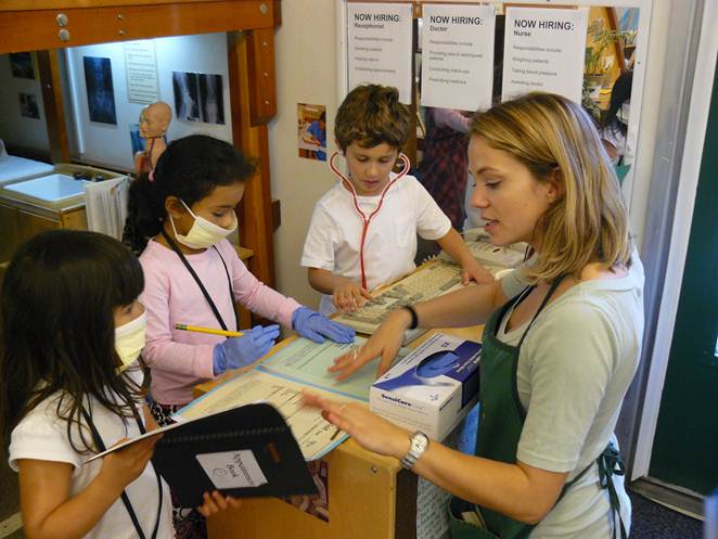 Children and teacher playing medical office